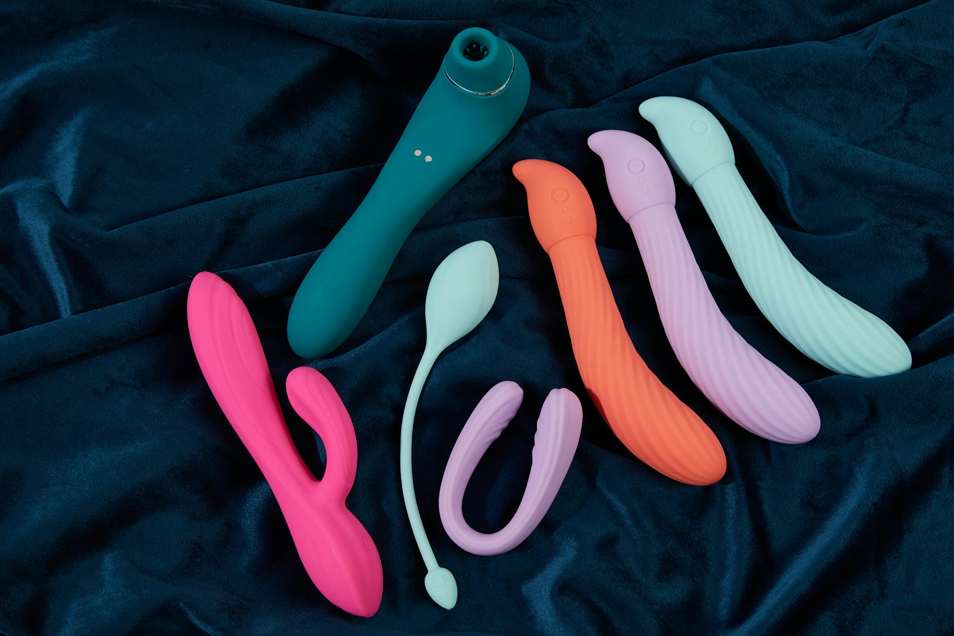 Yellow silicone vibrator surrounded by fresh fruit on bright yellow surface