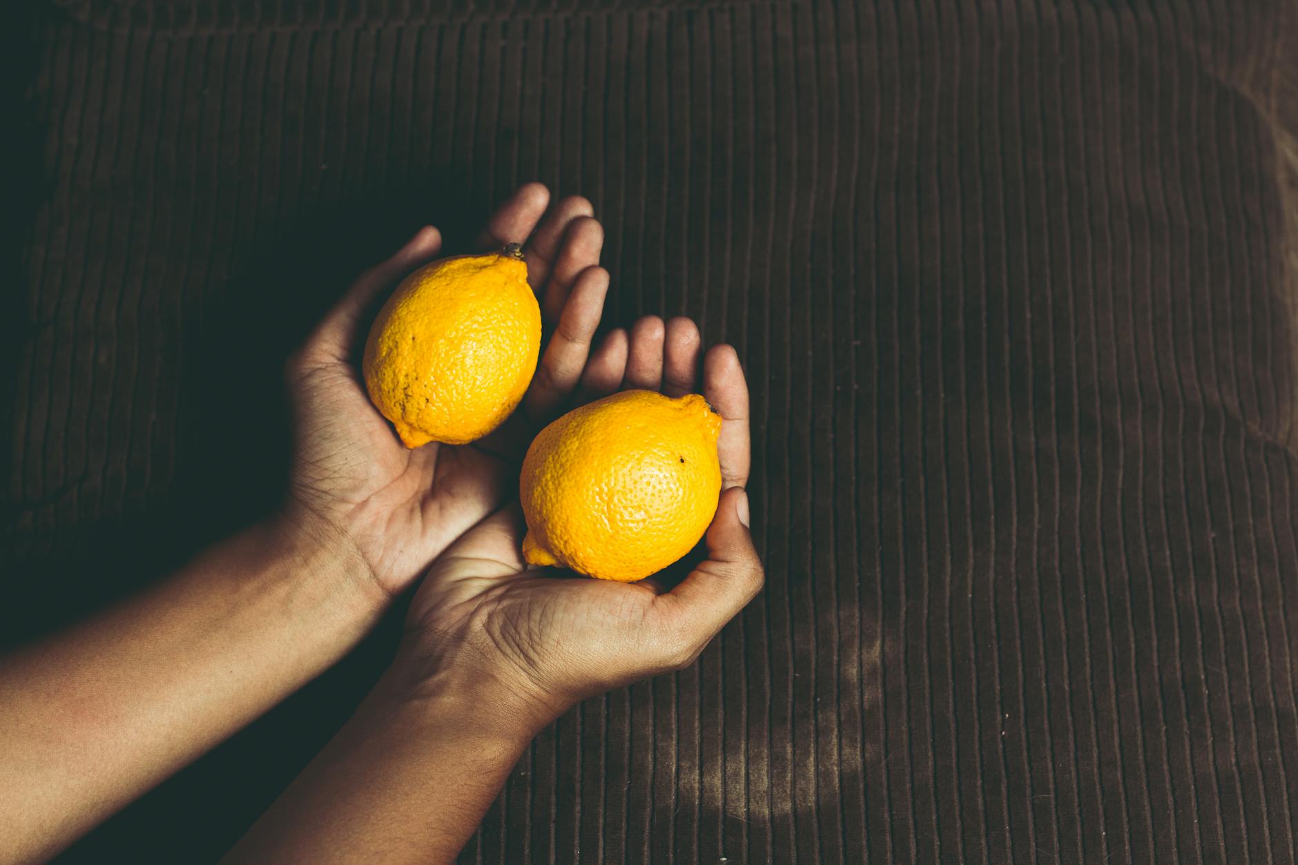 Bright yellow lemons arranged on a pastel green background, symbolizing freshness and vitality across life stages