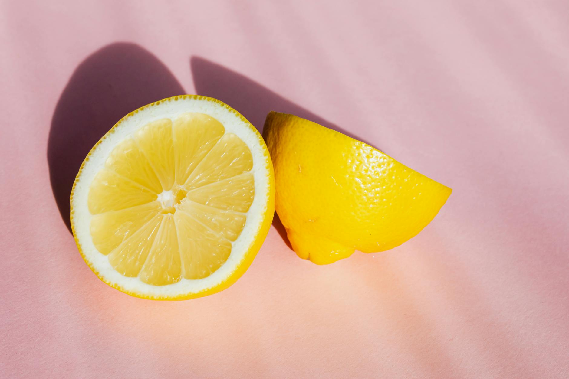 Fresh lemon halves on a pink background, symbolizing closeness and freshness