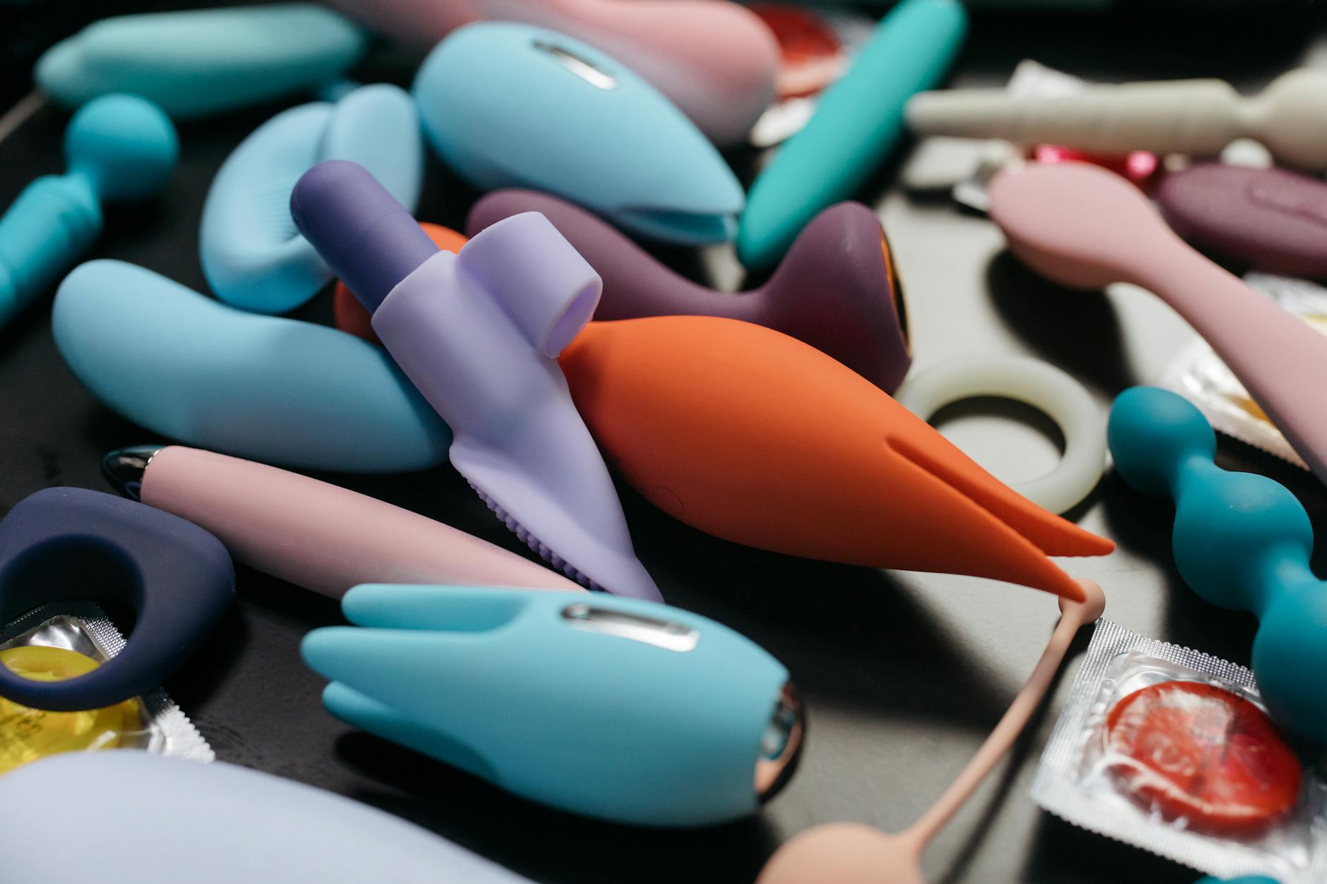 Close-up of hands holding a sleek blue vibrator against a purple background