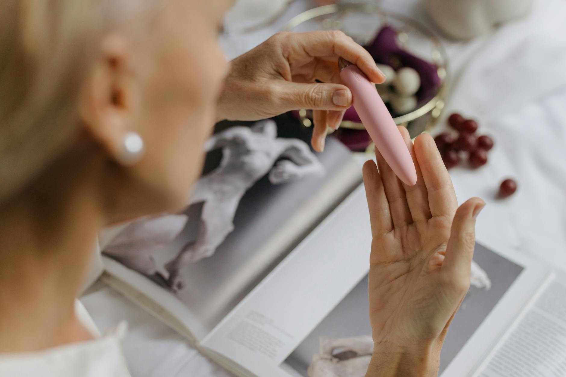A person holding a pink vibrator thoughtfully, symbolizing self-care and intimate connection