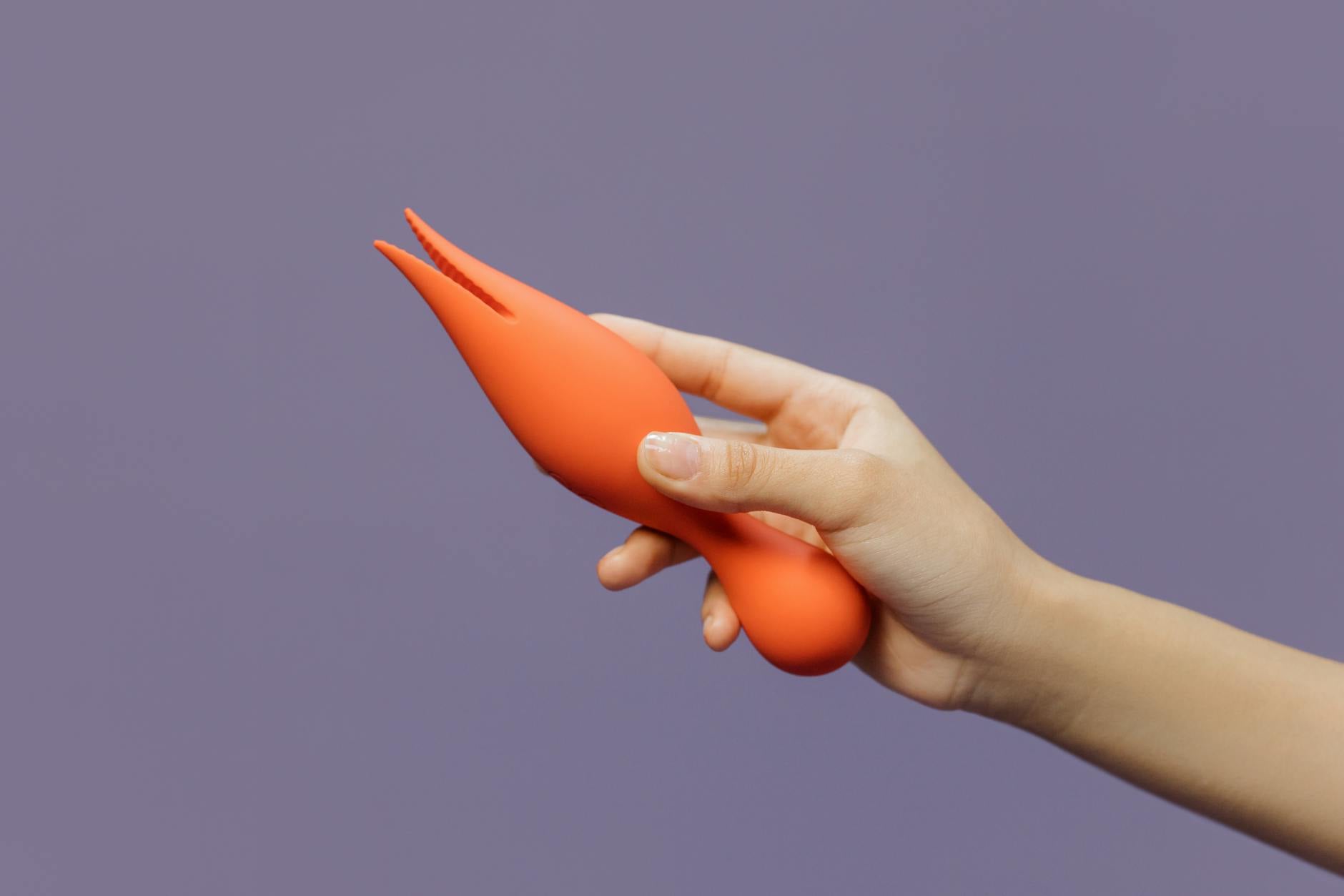 Hand holding a bright lemon vibrator against a purple background, representing sensory recovery and intimate healing