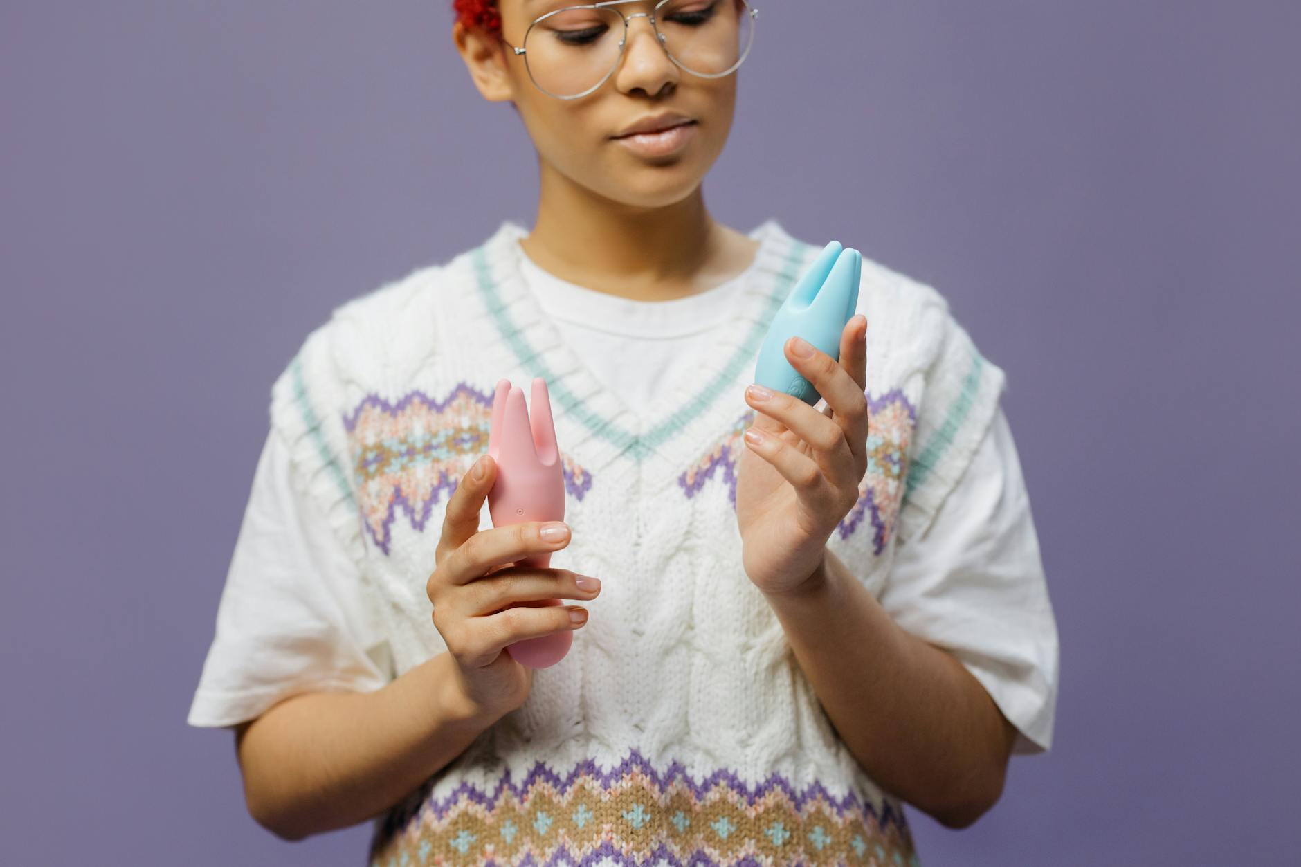 Woman holding a clitoral vibrator with a thoughtful expression, representing pleasure and self-care after menopause.