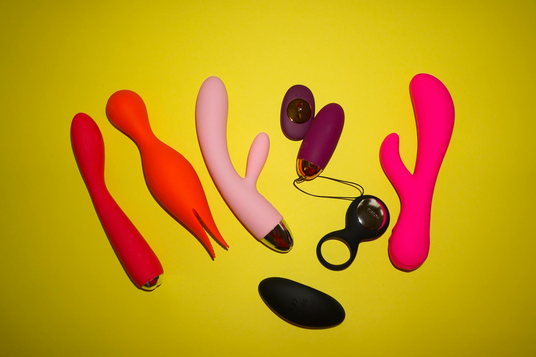 Studio arrangement of vibrant lemon-colored adult toys and clitoral vibrators on yellow background
